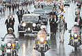 Инаугурационный парад Руссеф на Монументальной оси. Полицейские мотоциклы и телохранители окружают президентский «Роллс-Ройс», за которым следует кабриолет Cadillac De Ville 1968 года выпуска, на котором ездил вице-президент Мишел Темер