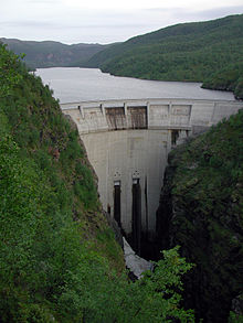 A white dam, built between two bodies of vegetation