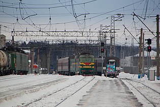 Пассажирский поезд с электровозом ЧС7 прибывает на станцию. Слева — грузовой поезд с электровозом ВЛ11