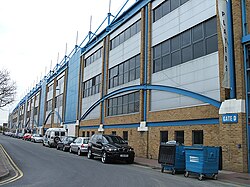 Внешний вид спортивного стадиона, с большим количеством синих деталей на фасаде.