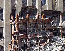 Обломок каркаса Всемирного торгового центра 7 на фоне поврежденного Верайзон-билдинг