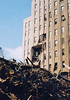 Повреждённый фасад здания со стороны Вашингтон-стрит, 210 (восток) и обломки Всемирного торгового центра 7
