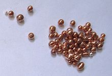 Несколько десятков металлических красновато-коричневых гранул. Они имеют блестящий вид, как будто на них нанесено целлофановое покрытие.