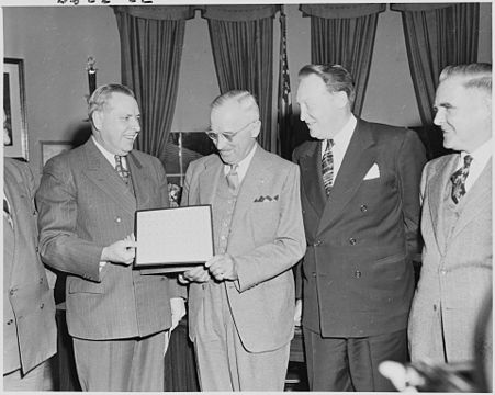 Дональдсон (слева) в Овальном кабинете вручает президенту Трумэну марки нового выпуска «Статуя Свободы» (апрель 1950)[≡]