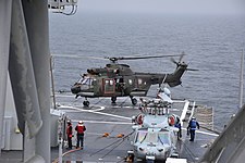 Посадка вертолёта AS532 Cougar Mk. II U2 Королевских ВВС Нидерландов на ВППл корабля во время учений BALTOPS-2016, на переднем плане — вертолёт MH-60S Seahawk Авиации ВМС США со сложенными лопастями несущего винта; USS Mount Whitney (LCC-20), 2016 год.