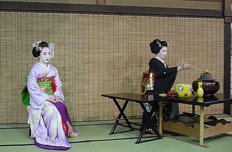 Проводящей церемонию «тэмаэ» (яп. 手前), гейше, ассистирует «хикаэ» (яп. 控え) — майко Коай