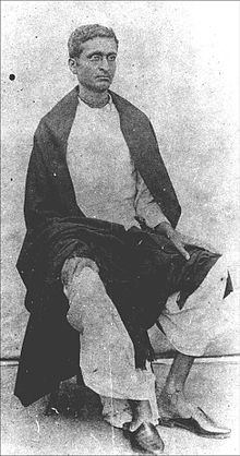 A photo of a sitting young Indian man wearing spectacles and looking to the right