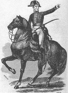 Black-and-white print of a man on horseback holding a saber and pointing to the viewer’s right. He wears a dark coat of early 1800s style, white breeches, black boots, and a bicorne hat worn side-to-side.