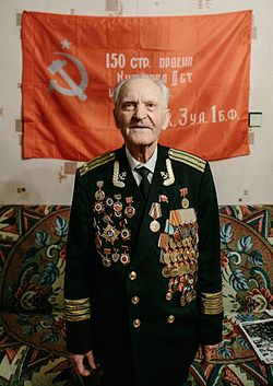 Николай Беляев на фоне копии Знамени Победы.