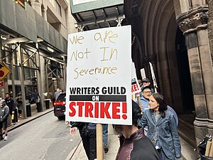 Колонна протестующих сценаристов с плакатами на съёмочной площадке сериала «Сорвиголова: Рождённый заново» в Нью-Йорке. Надпись на плакате ссылается на телесериал «Разделение», производство которого было заморожено в связи с забастовкой.